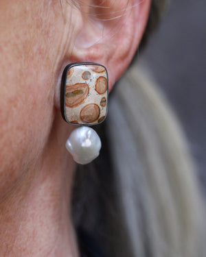 Close-up of leopard skin jasper stud earrings with baroque pearl drops showing earthy patterns and organic shapes in oxidized silver worn on ear