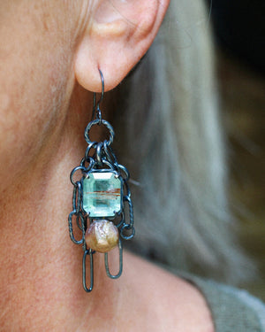 Close up of long gemstone chain earrings with aquamarine, pearl, copper rutile quartz, and oxidized sterling silver worn on ear.