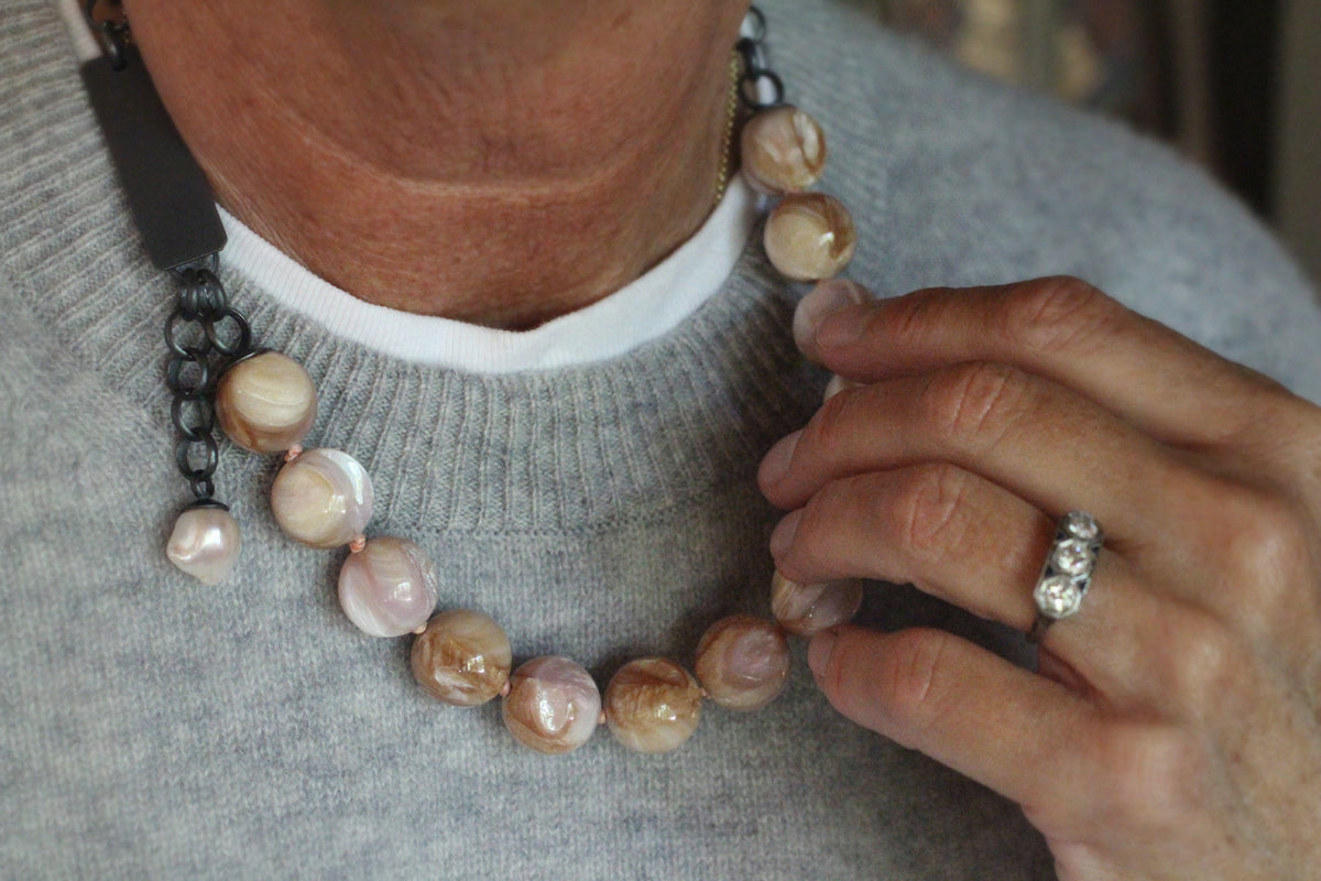 One-of-a-kind shell bauble necklace with oxidized sterling silver chain, front clasp, and small baroque pearl dangle on a white background.