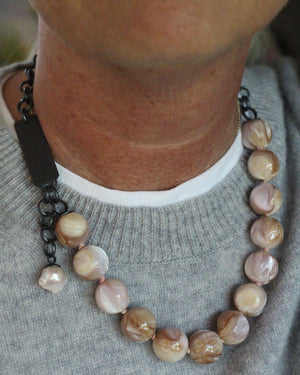 Natural shell bauble necklace worn with a gray sweater, showing blush pink, cream, honey, and lavender shell beads with oxidized silver chain.