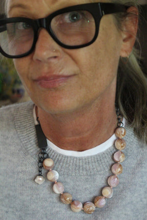 Natural shell bauble necklace worn with a gray sweater, showing blush pink, cream, honey, and lavender shell beads with oxidized silver chain.