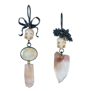 Mismatched Calavera earrings with carved pearl skulls, opalized druzy, pink lithium quartz, oxidized silver bow and floral details, and 14k gold accents on white background.