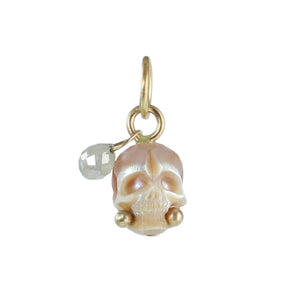 Hand-carved cream pearl skull charm with a silver diamond dangle and recycled 14k gold accents on a white background.