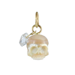 Hand-carved cream pearl skull charm with a clear Herkimer diamond dangle and recycled 14k gold rings on a white background.