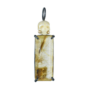 Rectangular golden rutile quartz in a emerald cut with a carved pearl skull on top. Oxidized sterling silver with 14k gold accents. 