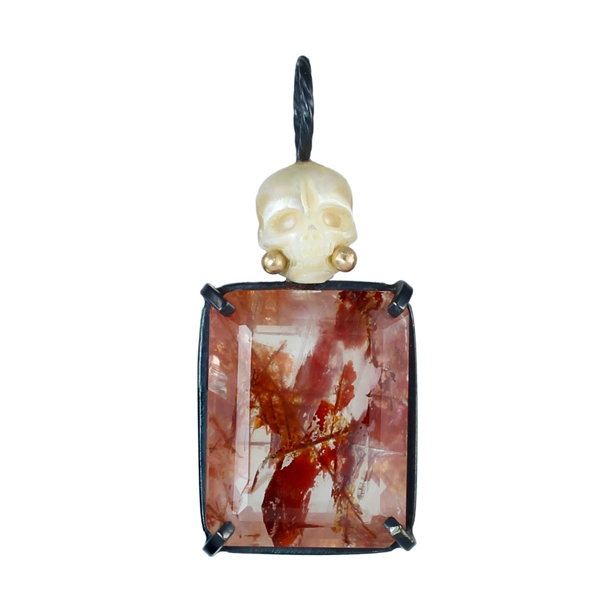 Pearl Calavera pendant with a hand-carved skull, recycled 14k gold details, and faceted red rutile quartz set in oxidized sterling silver on a white background.