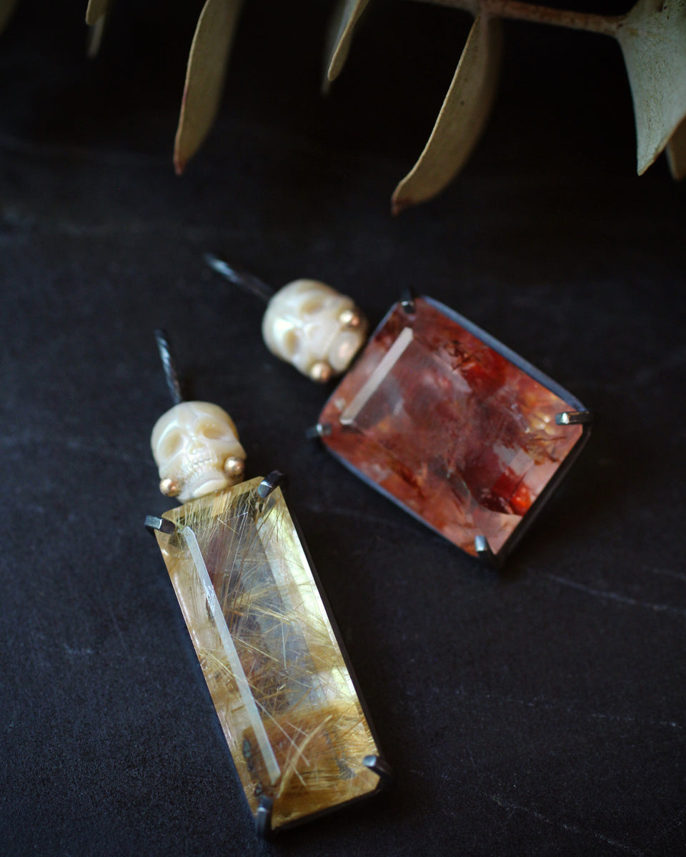 Rectangular golden rutile quartz in a emerald cut with a carved pearl skull on top. Oxidized sterling silver with 14k gold accents. 