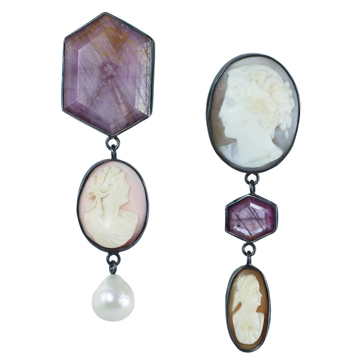 Symmetrical but mismatched drop earrings in oxidized silver and 14k gold featuring antique shell cameos, a large pink sapphire, ruby slice, and freshwater pearl drops on a white background.