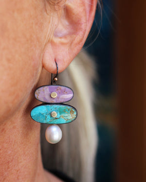 Woman wearing colorful phosphosiderite and turquoise earrings with pearl drops in oxidized silver and gold, showing scale and movement