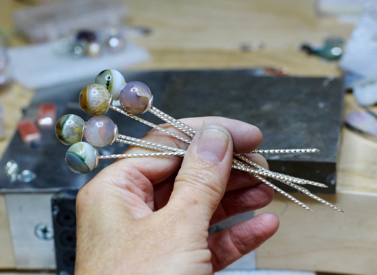 Set of six sterling silver cocktail picks with twisted wire stems and colorful phantom quartz tops on a white background.