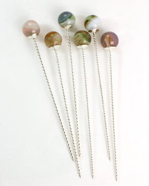 Set of six sterling silver cocktail picks with twisted wire stems and colorful phantom agate tops on a white background.