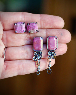 Two pairs of handmade pink cobalto calcite earrings displayed in a hand. Simple gemstone studs sit above longer earrings with fused silver chain and gold filled accents.