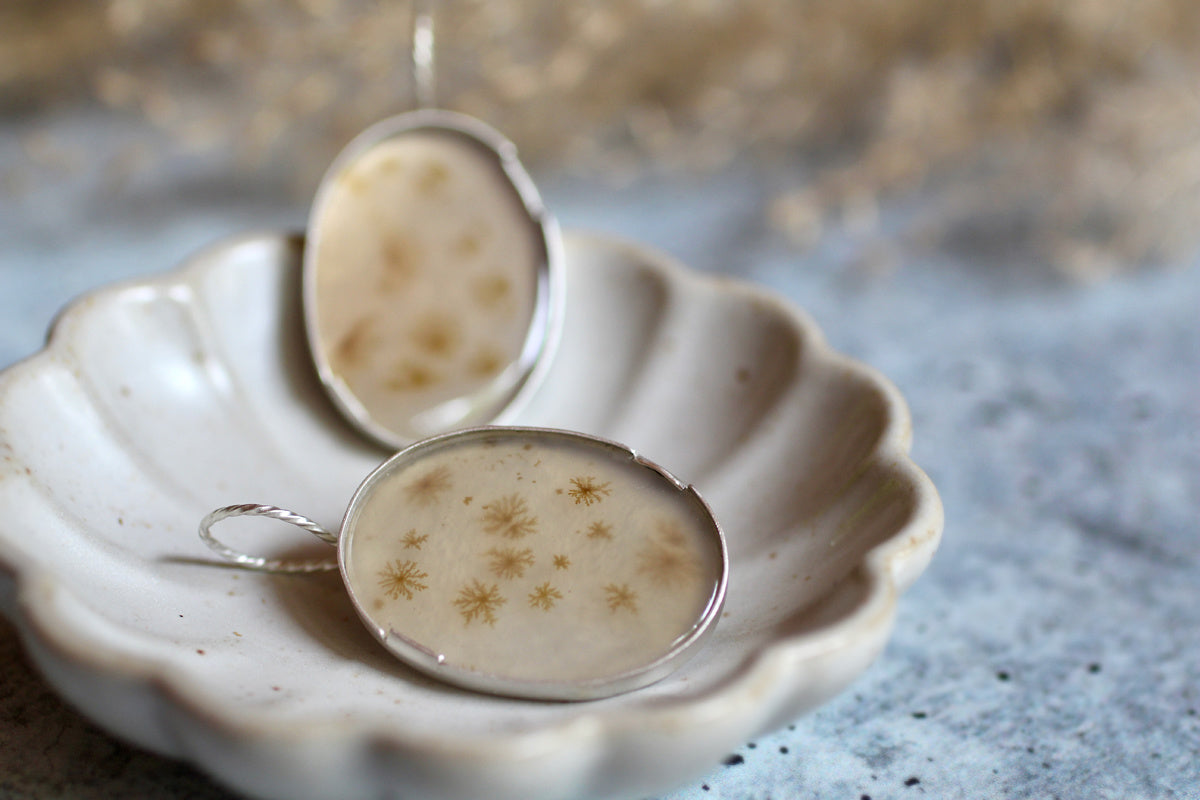 Dendritic agate earrings in matte sterling silver with soft brown botanical-like inclusions set in oval handmade bezels floating on a white background.