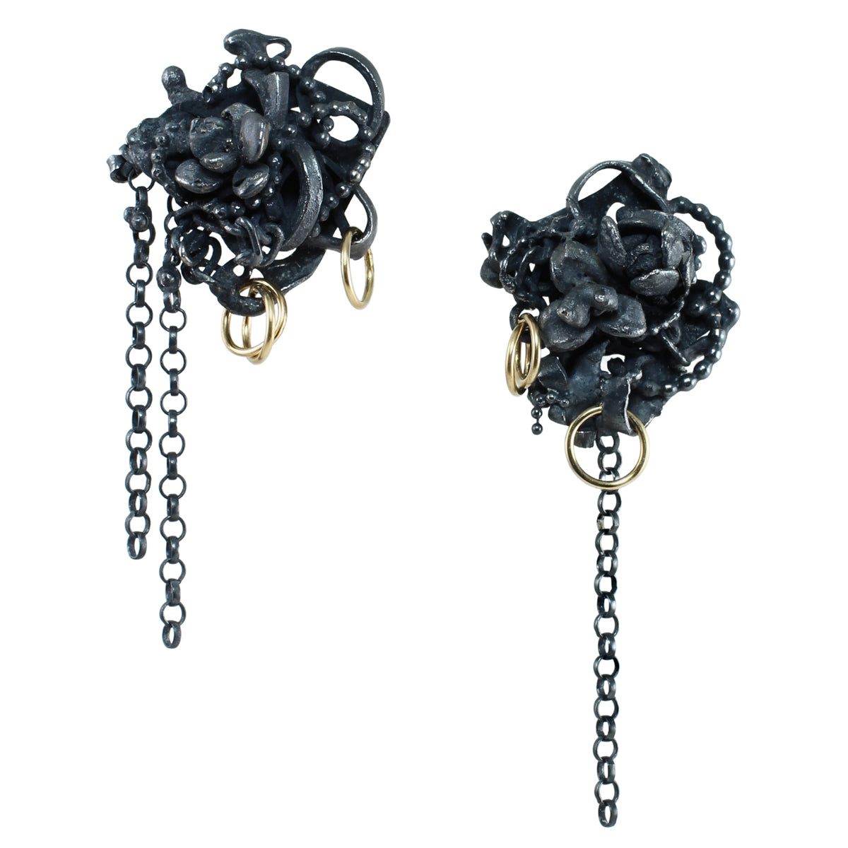 Asymmetrical Fragments earrings made from fused oxidized sterling silver with tiny flower castings, 14k gold fill rings, and dangling silver chains pictured on a clean white background.