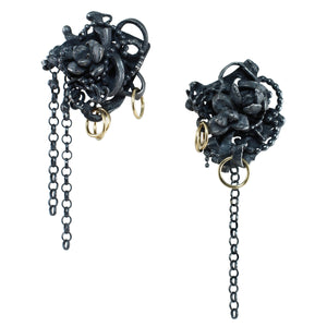 Asymmetrical Fragments earrings made from fused oxidized sterling silver with tiny flower castings, 14k gold fill rings, and dangling silver chains pictured on a clean white background.