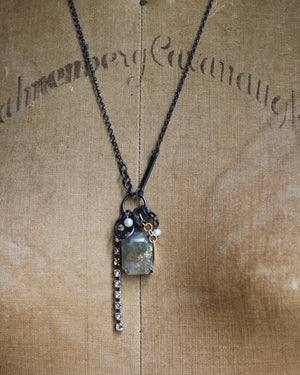 Close-up of the green sunstone necklace on a vintage dress form, showing the faceted stone’s coppery-gold shimmer, pearls, oxidized silver details and crystal chain.