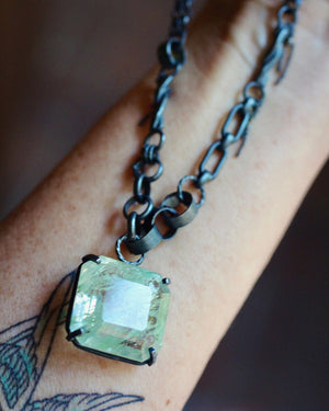 Close up of Garden quartz statement necklace draped over a forearm, showing the mixed link oxidized silver chain and pale green pendant.