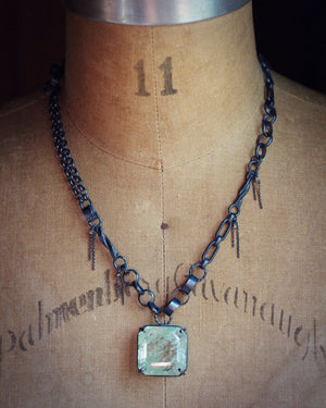 Garden quartz statement necklace displayed on a dress form, showing the mixed link oxidized silver chain and pale green pendant.