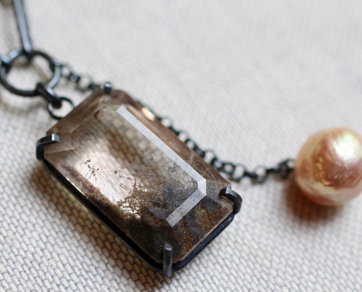Rutile quartz talisman necklace with baroque pearl and mixed oxidized silver chain on white background.