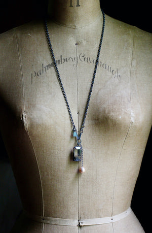 Long oxidized silver rutile quartz and baroque pearl necklace displayed on a dress form.