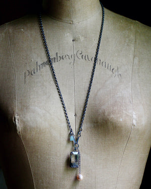 Long oxidized silver rutile quartz and baroque pearl necklace displayed on a dress form.