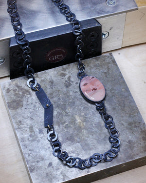 Imperial jasper necklace with handcrafted oxidized chain and gold accents resting on metal surface, highlighting botanical tab detail.
