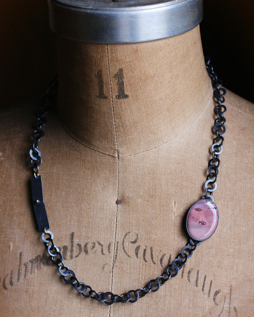 Imperial jasper necklace with oval pink patterned stone, oxidized silver handcrafted chain, and small 14k gold accents on white background.