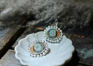 Imperial jasper eye earrings displayed in a trinket dish on an aged wood crate.