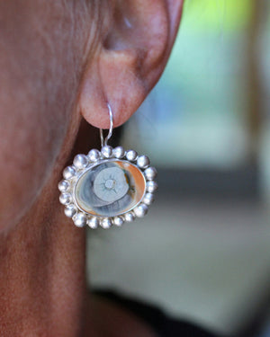 Close-up of one Imperial jasper eye earring worn on the ear, with cream, blue, and ochre tones framed in brushed silver.