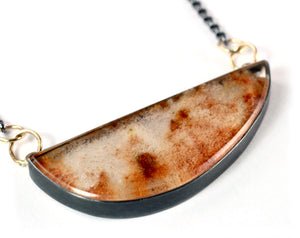 Close-up of a lodolite garden quartz necklace with rust and cream inclusions, set in oxidized sterling silver with 14k gold details photographed on a white background.
