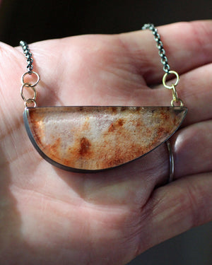 Garden quartz necklace held in hand to show the scale and natural rust, cream, and smoky inclusions within the lodolite stone.