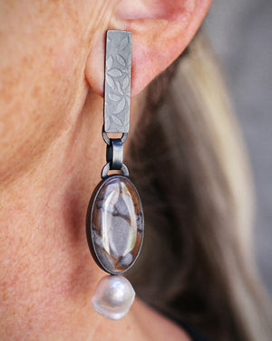 Mismatched Wonderstone and Mushroom Jasper earrings with one baroque pearl, set in oxidized sterling silver with embossed rectangular tabs worn.