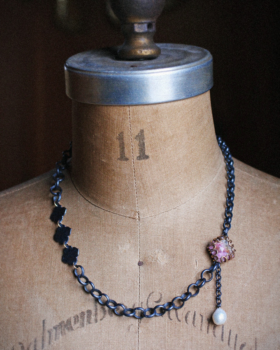 Oxidized sterling silver mixed chain necklace with pink cobalt calcite set in 14k gold loops and a dangling pearl on white background