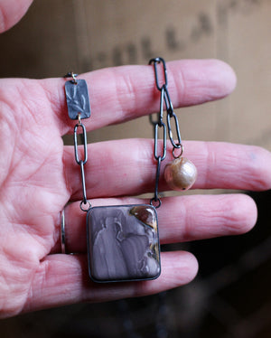 Hand holding jasper and pearl necklace showing square jasper pendant and darkened silver chain detail