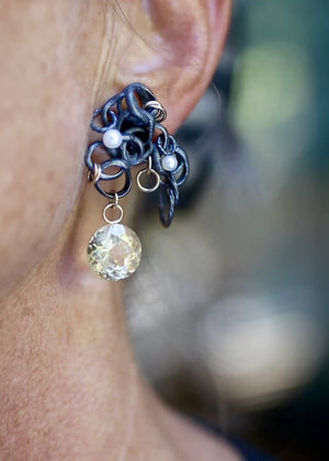 Close-up video of a Fragments earring worn on the ear, with fused oxidized sterling silver, pearls, gold accents, and a large round faceted citrine drop. Shows movement and scale. 