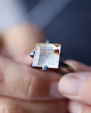 Video of one-of-a-kind square white topaz ring with golden inclusions and oxidized sterling silver setting, shown held in fingers.