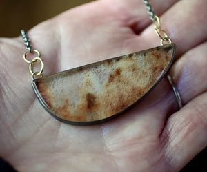 Video of garden quartz necklace held in hand to show the scale and natural rust, cream, and smoky inclusions within the lodolite stone.