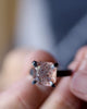 Video of handmade modernist sunstone ring with warm orange and copper inclusions in a dark oxidized sterling silver setting, shown held by fingers.