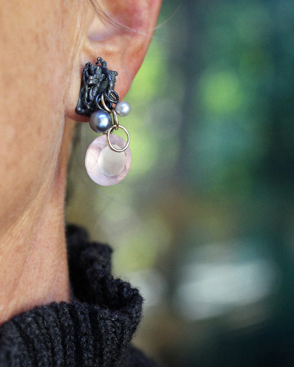 One-of-a-kind Fragment earrings with fused, textured oxidized sterling silver, luminous silver and white pearls, warm gold fill rings, and large faceted rose quartz drops in a soft translucent pink photographed on a white background.