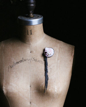 Large shell brooch worn on dress form, with oxidized silver chain fringe hanging approximately 7 inches, creating a dramatic vertical statement.