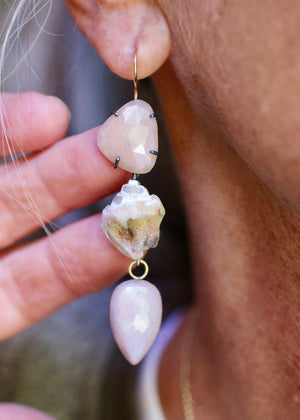 Close-up of long peach moonstone and druzy shell earring with a faceted pink moonstone drop, worn on the ear.