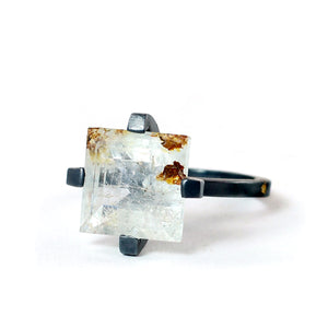 Square faceted white topaz ring with golden inclusions, held in a four-prong oxidized sterling silver setting.